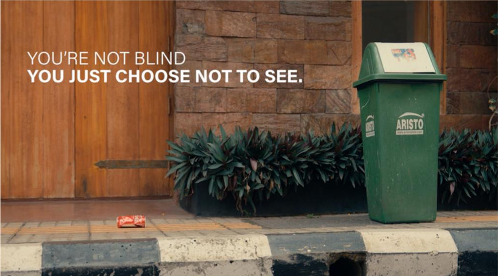 A bin beside a doorway with the line: you're not blind, you just choose not to see