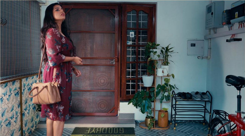 A woman stepping out of a Kerala doorway with a handbag
